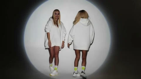 Two blondes with bright makeup in white hoodies have fun on camera Stock Footage 199251625