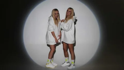 Two blondes with bright makeup in white hoodies have fun on camera Stock Footage 199251978