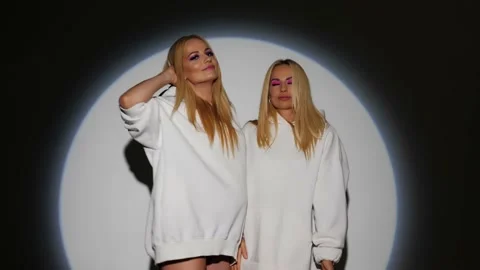 Two blondes with bright makeup in white hoodies have fun on camera Stock Footage 199252167