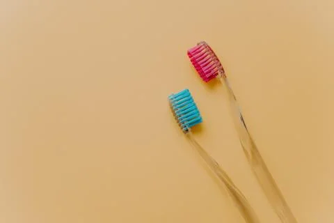 Two blue and red plastic toothbrushes isolated over yellow background with em Foto stock