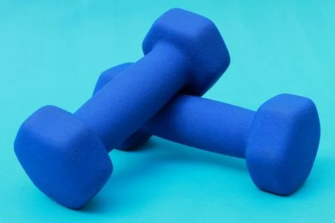 Two blue barbells stacked on a blue background Stock Photos