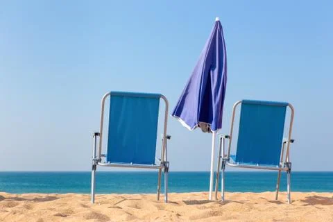Two blue beach chairs and parasol at sea Stock Photos