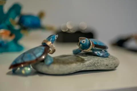 Two blue cheramic turtles on round stone decoration holding wedding rings. Stock Photos