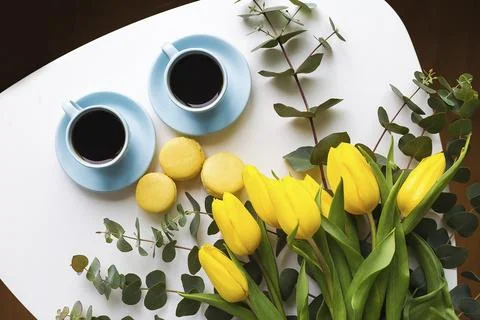 Two blue cup of coffee with yellow tulips on an old table, top view Stock Photos