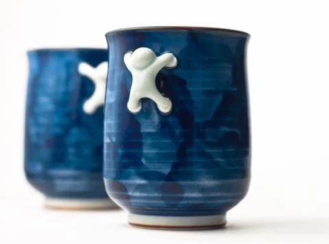 Two blue cups with crawling men as handles Stock Photos