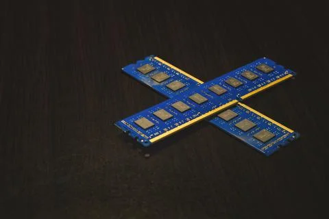 Two blue desktop RAM modules in X shape on dark wood surface. Stock Photos