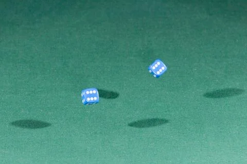 Two blue dices falling on a green table Stock Photos