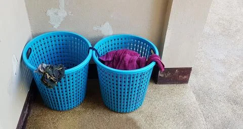 Two blue plastic baskets of used laundry put in corners of the room Stock Photos