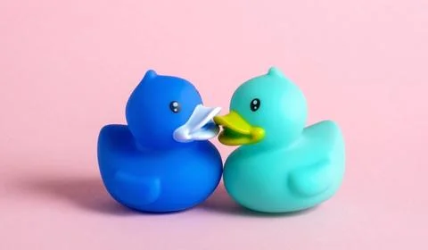 Two blue rubber ducks  are kissing on pink background. Foto stock