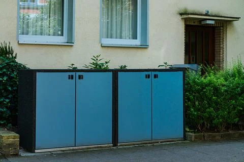 Two blue storage cabinets positioned near a residential building Stock Photos