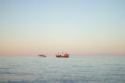Two boats float on a calm sea under the pastel sky in Batumi Stock Photos