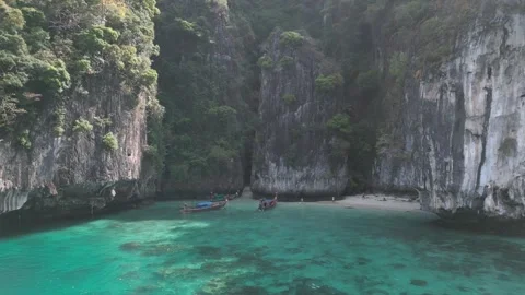 Two boats halted in tranquil bay by beach, under imposing cliffs, epitomize Stock Footage 267366633