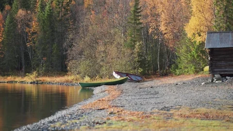 Two boats lay peacefully on a pebble beach, surrounded by the vibrant hues Stock Footage 277640444