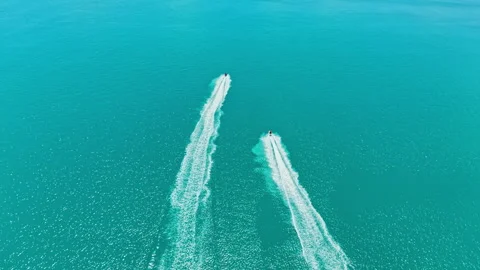 Two boats move fast on clear blue water in sunny weather near a coastline during Stock Footage 337945715
