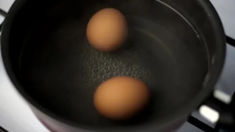 Two boiled brown eggs in a pot of boiled water Stock Footage 179921380