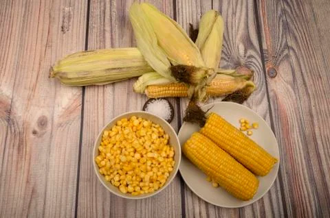 Two boiled ears of corn, corn kernels, coarse salt and raw ears of corn on a  Stock Photos