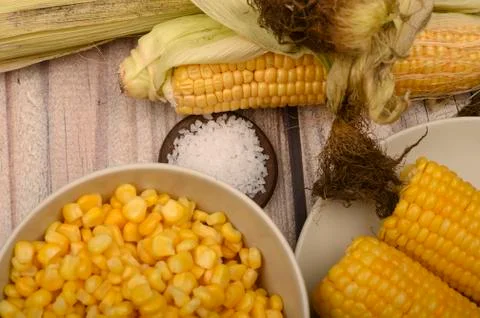 Two boiled ears of corn, corn kernels, coarse salt and raw ears of corn on a  Stock Photos