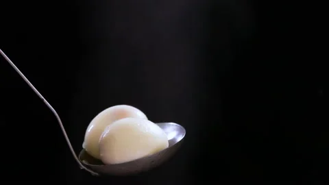 Two boiled eggs on a ladle with steam. On a black background Stock Footage 154928143
