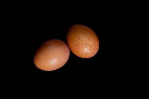 Two boiled eggs in orange shells on a black background, Stock Photos