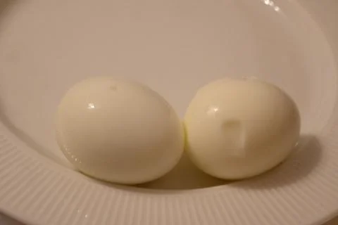 Two boiled eggs on a white plate Stock Photos