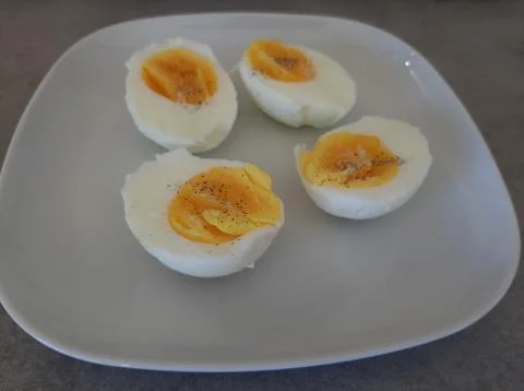 Two boiled sliced eggs arranged on a white plate Stock Photos