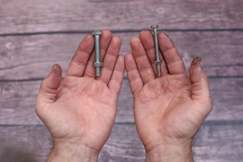 Two bolts and nuts in working men's hands. Stock Photos