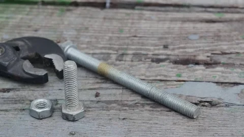 Two bolts and two nuts next to the adjustable wrench on the table Vídeos de archivo 224990953