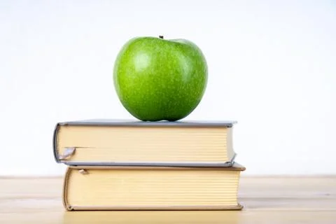 Two books and green apple on the wooden table Stock-Fotos