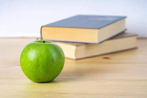 Two books and green apple on the wooden table Stock-Fotos