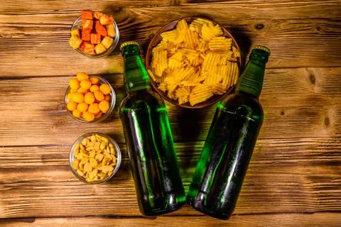 Two bottles of beer and different snacks on wooden table. Top view Stock Photos