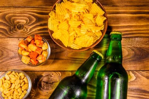 Two bottles of beer and different snacks on wooden table. Top view Stock Photos