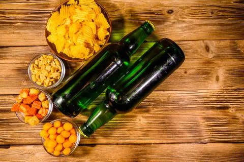 Two bottles of beer and different snacks on wooden table. Top view Stock Photos