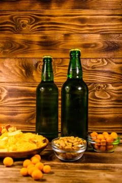 Two bottles of beer and different snacks on wooden table Stock Photos