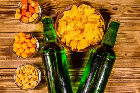 Two bottles of beer and different snacks on wooden table. Top view Stock Photos
