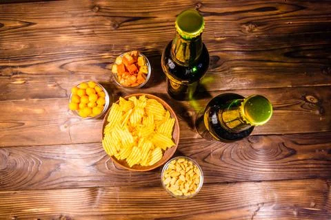 Two bottles of beer and different snacks on wooden table. Top view Stock Photos