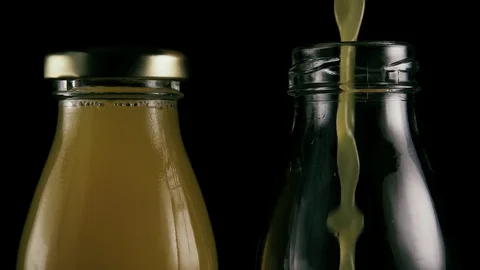 Two bottles on a black background with juice. Slow motion Stock Footage 75991832