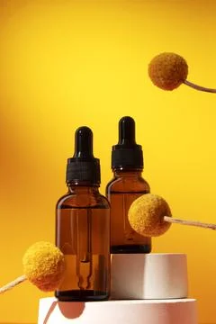 Two bottles different size with serum with floral extracts craspedia flowers. Stock Photos