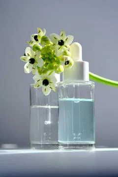 Two bottles with a dropper with spring flowers. Stock Photos
