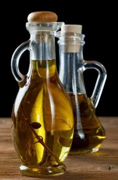 Two bottles of olive oil on rustic table Stock Photos