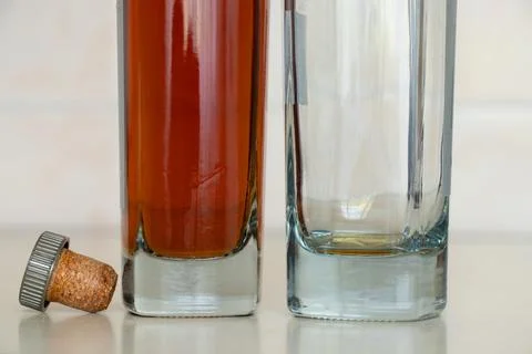 Two bottles, one full one empty with cognac and a cork on the table in the .. Stock Photos