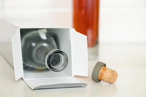 Two bottles, one full one empty in boxes with cognac and a cork on the table  Stock-Fotos