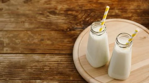 Two bottles of organic rustic milk on wooden table Stock Photos