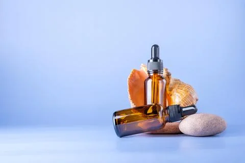 Two bottles with a pipette with a sea shell on stones. Stock Photos