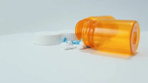 Two bottles spilled pills rotating LtoR white blue Stock Footage 315404997