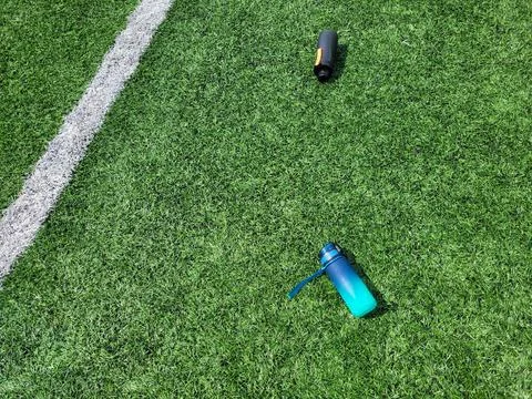 Two bottles of water are lying on the green football field Stock Photos