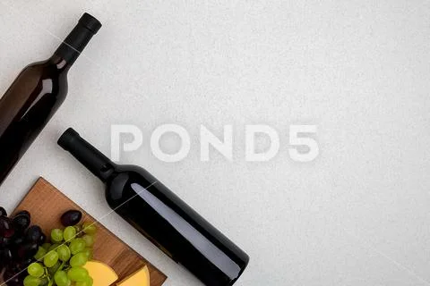 Two bottles of white and red wine, cheese and grapes. Top view Stock Photos