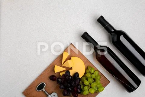 Two bottles of white and red wine, cheese and grapes. Top view Stock Photos