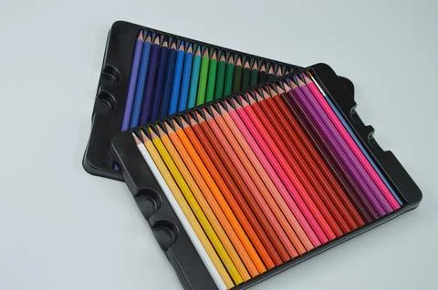 Two boxes with sets of bright colored pencils on a white background. Statione Stock Photos