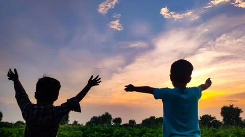 Two boy hands up and looking at scenic sunset view Stock Photos