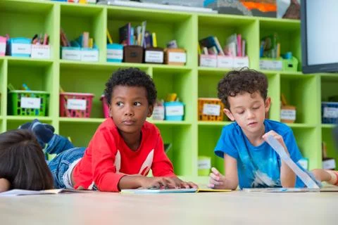 Two boy kid lay down on floor and reading tale book  in preschool library,Kin Stock Photos